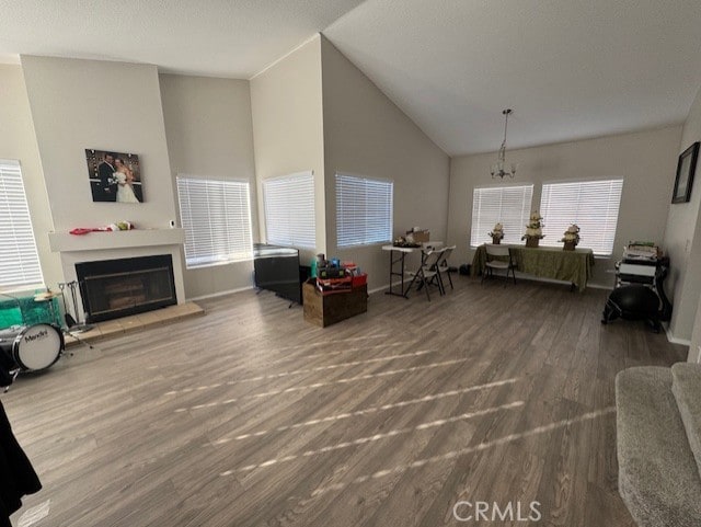 living room featuring high vaulted ceiling, wood-type flooring, and an inviting chandelier