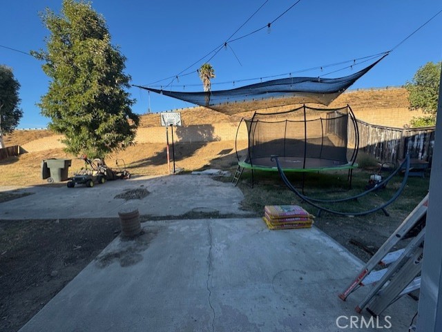 view of yard with a trampoline and a patio area