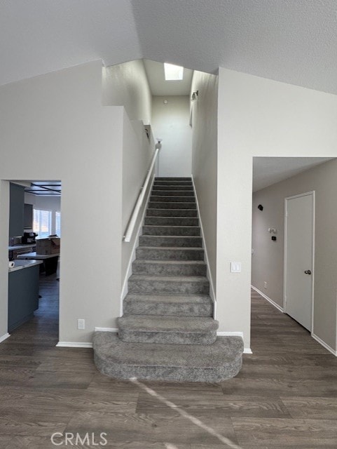 stairway with hardwood / wood-style flooring and vaulted ceiling with skylight