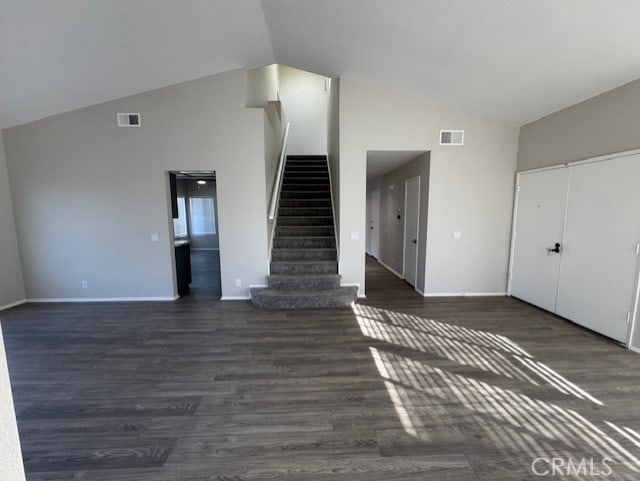 unfurnished living room with dark wood-type flooring and high vaulted ceiling