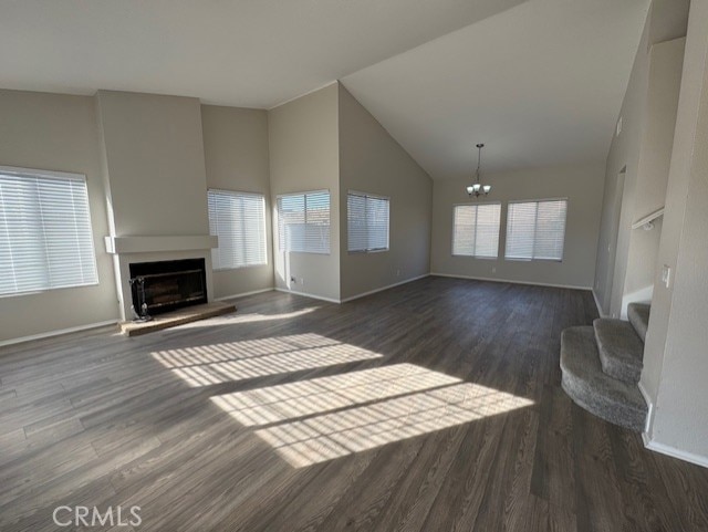 unfurnished living room with dark hardwood / wood-style flooring, a chandelier, and high vaulted ceiling