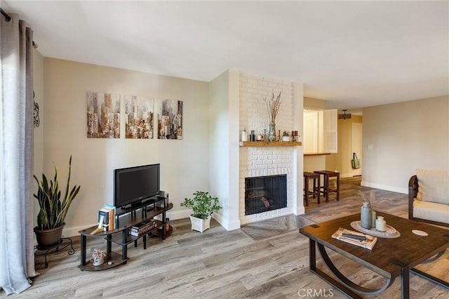 living room with wood-type flooring and a brick fireplace