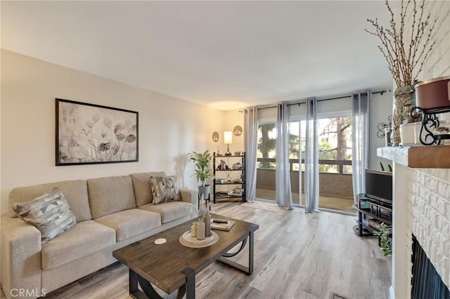 living room with a stone fireplace and light hardwood / wood-style floors