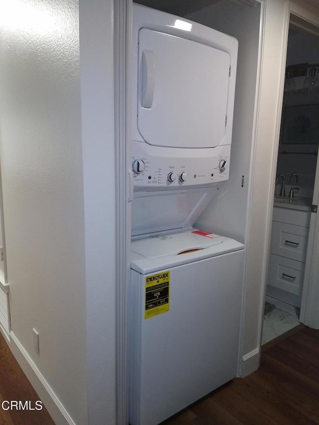 clothes washing area featuring sink, dark hardwood / wood-style flooring, and stacked washer and dryer