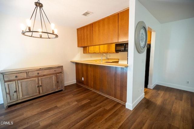 kitchen featuring kitchen peninsula, sink, a notable chandelier, dark hardwood / wood-style floors, and hanging light fixtures