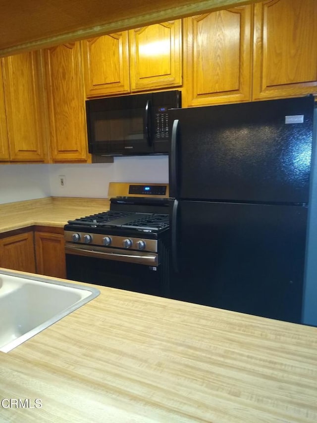 kitchen featuring sink, black appliances, and hardwood / wood-style flooring