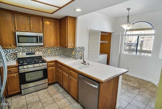 kitchen with pendant lighting, sink, decorative backsplash, appliances with stainless steel finishes, and kitchen peninsula