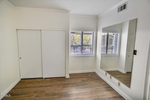 unfurnished bedroom with ornamental molding, dark wood-type flooring, and a closet