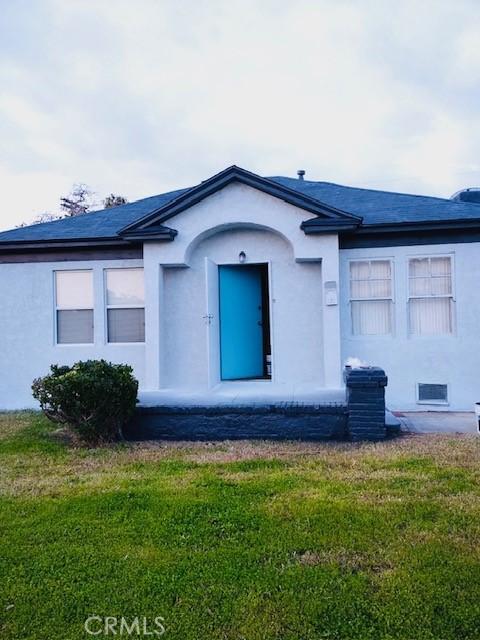 doorway to property with a yard and stucco siding