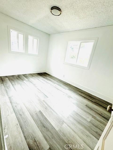 empty room with hardwood / wood-style floors and a textured ceiling