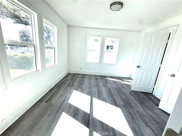 spare room featuring dark wood-style floors and baseboards