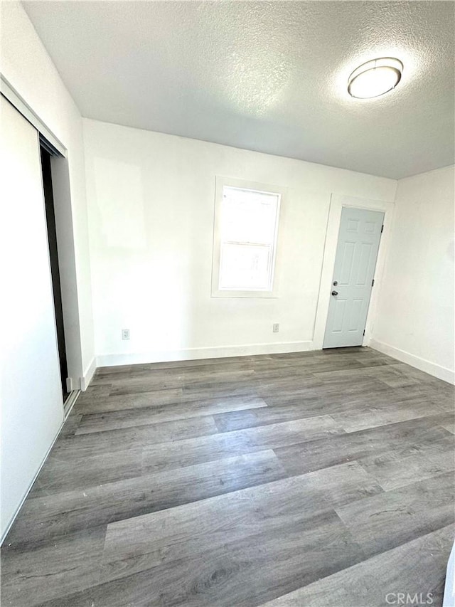 spare room featuring a textured ceiling, baseboards, and wood finished floors