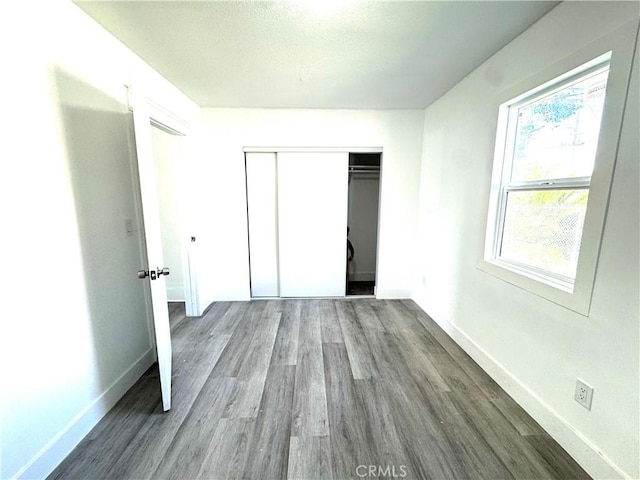 unfurnished bedroom with a closet, baseboards, and wood finished floors