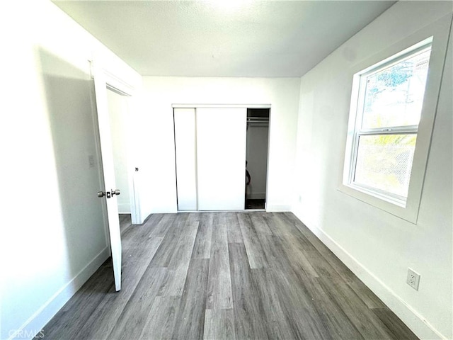 unfurnished bedroom featuring a closet, wood finished floors, and baseboards