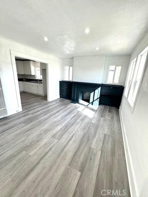 interior space with recessed lighting, a sink, a textured ceiling, wood finished floors, and baseboards