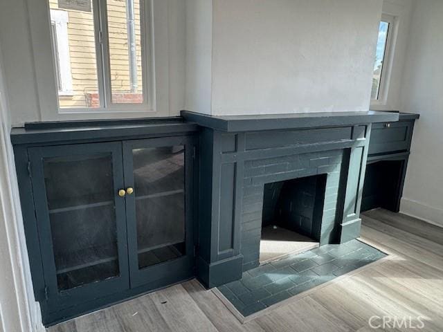 room details featuring a fireplace with flush hearth, baseboards, and wood finished floors