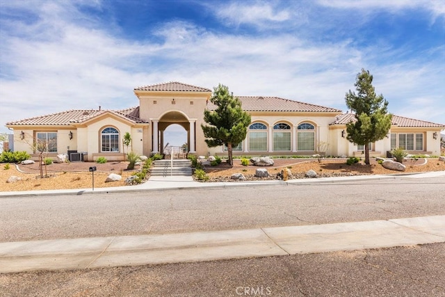 mediterranean / spanish-style home with central AC unit