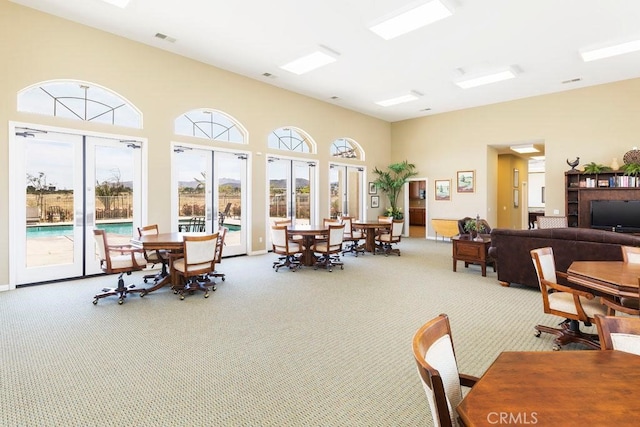 carpeted dining room with a high ceiling and visible vents