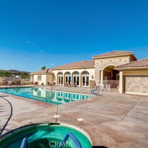 pool featuring a patio area, fence, and a hot tub