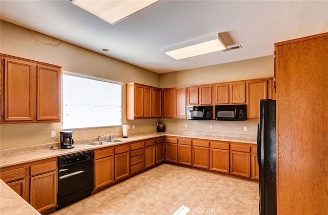 kitchen featuring brown cabinets, light countertops, visible vents, a sink, and black appliances