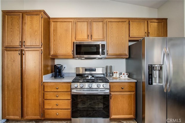 kitchen featuring lofted ceiling, brown cabinetry, stainless steel appliances, and light countertops