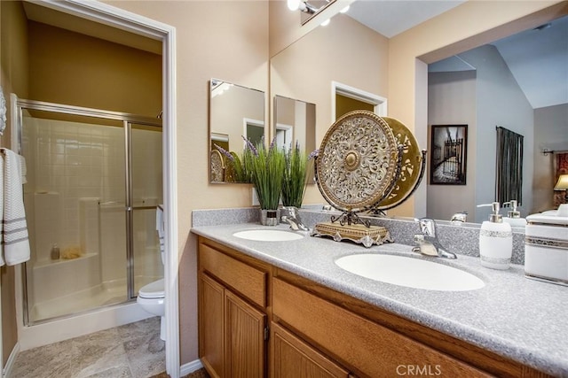 bathroom with double vanity, a sink, toilet, and a shower stall