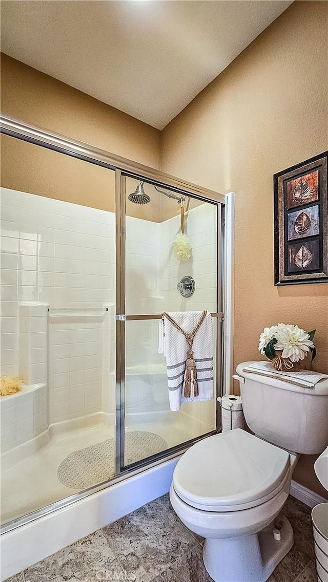 full bathroom with toilet, a shower stall, baseboards, and tile patterned floors