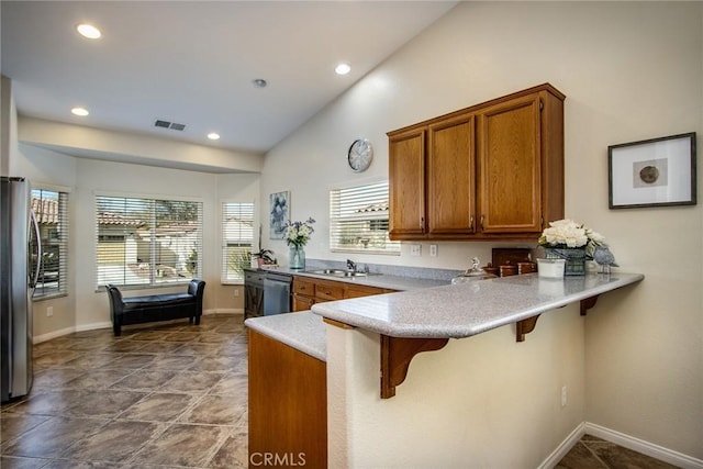 kitchen with a peninsula, a breakfast bar, a sink, light countertops, and freestanding refrigerator