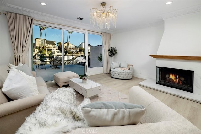 living room with a fireplace, hardwood / wood-style floors, a notable chandelier, and ornamental molding