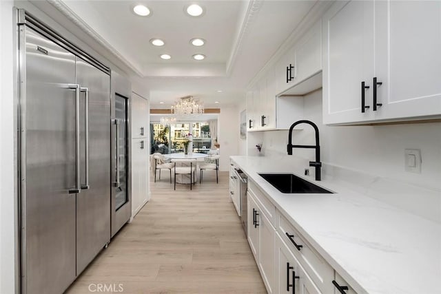 kitchen featuring an inviting chandelier, white cabinets, sink, appliances with stainless steel finishes, and light hardwood / wood-style floors