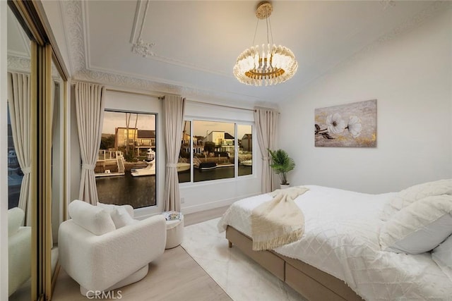 bedroom featuring lofted ceiling, light wood-type flooring, a tray ceiling, and a chandelier