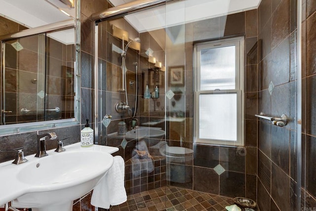 bathroom with a shower with shower door, backsplash, and sink