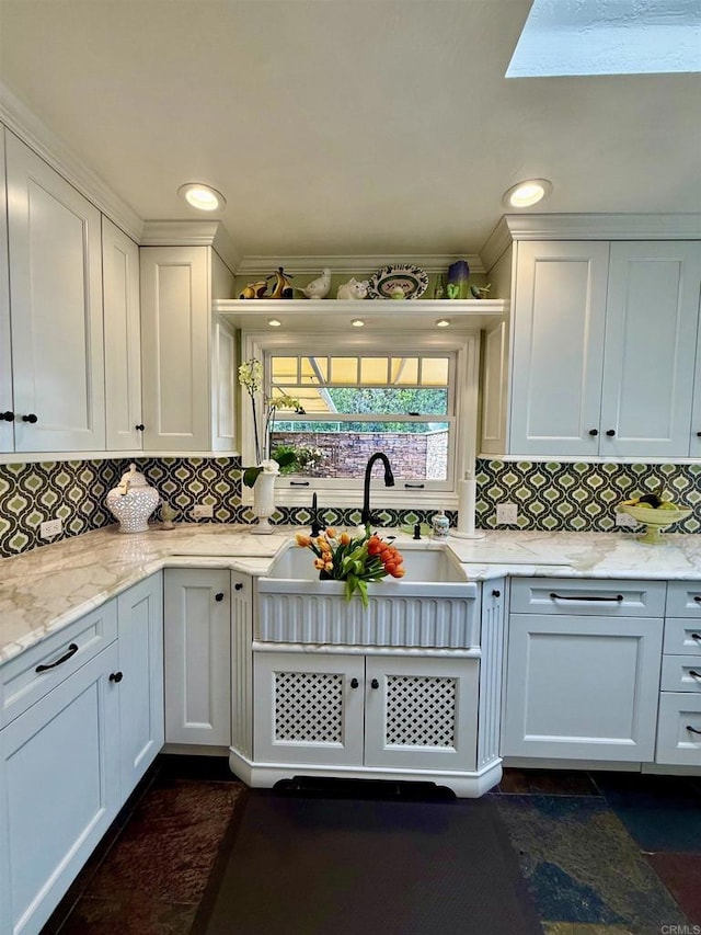 kitchen featuring light stone counters, sink, and white cabinetry