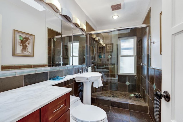 bathroom featuring a wealth of natural light, an enclosed shower, and toilet