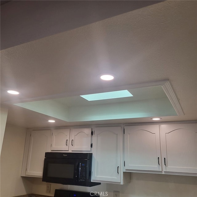 details with white cabinetry and a tray ceiling