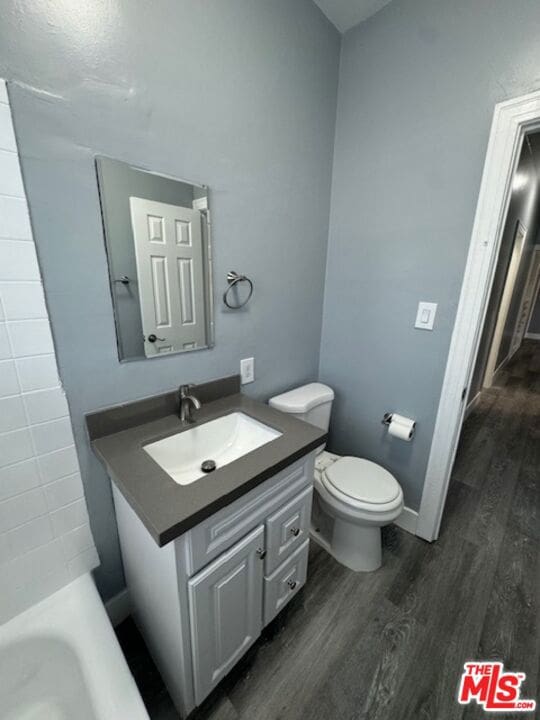 bathroom featuring a washtub, hardwood / wood-style floors, vanity, and toilet