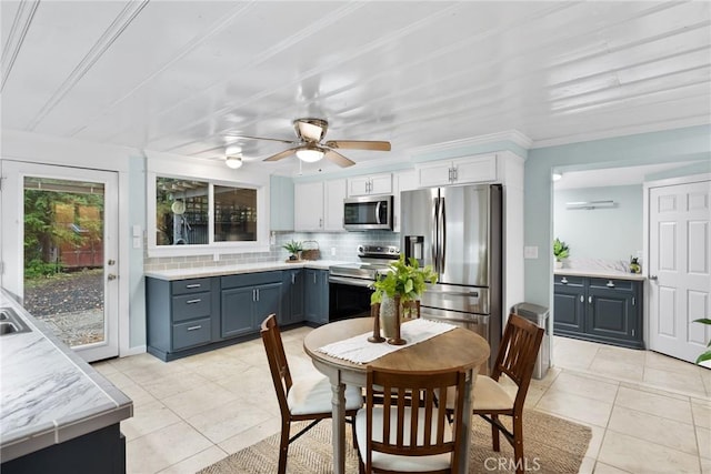 kitchen with backsplash, white cabinets, ceiling fan, light tile patterned floors, and stainless steel appliances