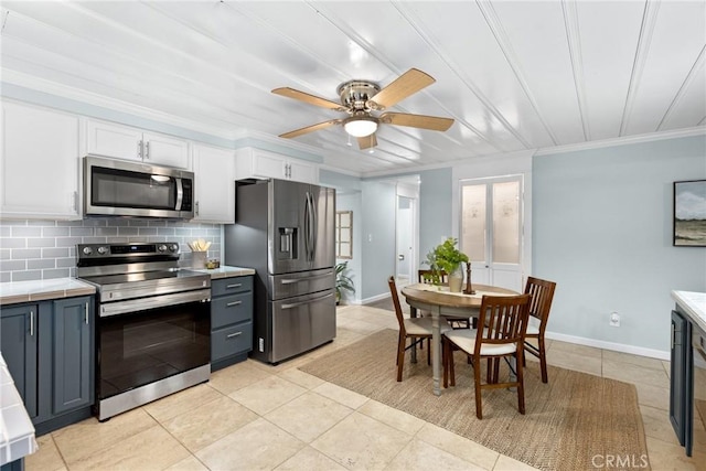 kitchen with appliances with stainless steel finishes, backsplash, ceiling fan, light tile patterned floors, and white cabinetry