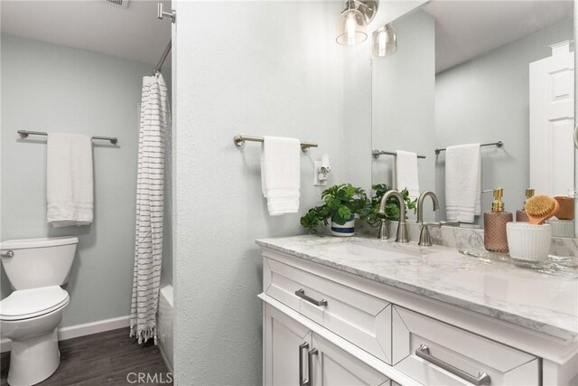 full bathroom featuring toilet, shower / tub combo with curtain, vanity, and hardwood / wood-style flooring