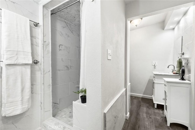 bathroom with hardwood / wood-style floors, vanity, and a tile shower