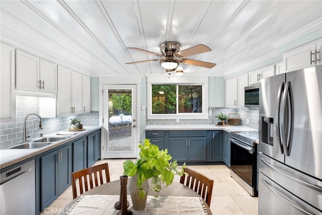 kitchen featuring a sink, ceiling fan, stainless steel appliances, blue cabinetry, and backsplash