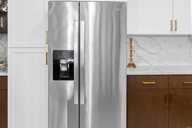 kitchen featuring white cabinets, stainless steel fridge with ice dispenser, backsplash, and light stone countertops