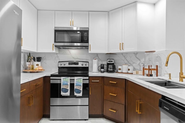 kitchen with white cabinets, appliances with stainless steel finishes, backsplash, and sink