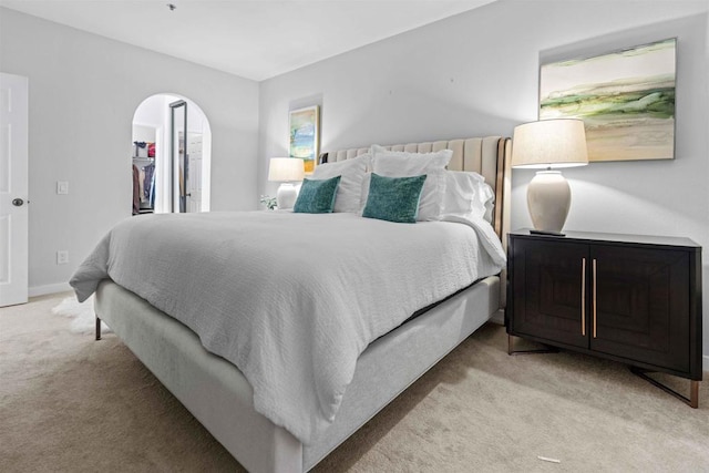 bedroom with a walk in closet, a closet, and light colored carpet