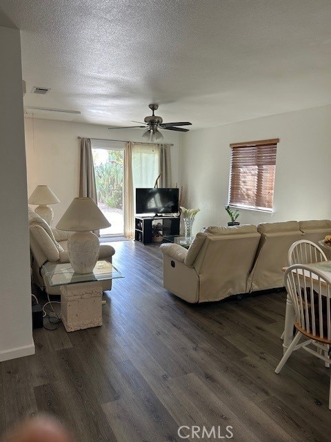 living room with plenty of natural light, dark wood-type flooring, and ceiling fan