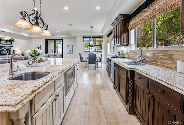 kitchen with stainless steel microwave, decorative backsplash, light stone counters, and sink