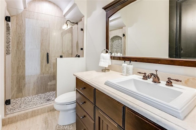 bathroom featuring toilet, a shower with shower door, and vanity