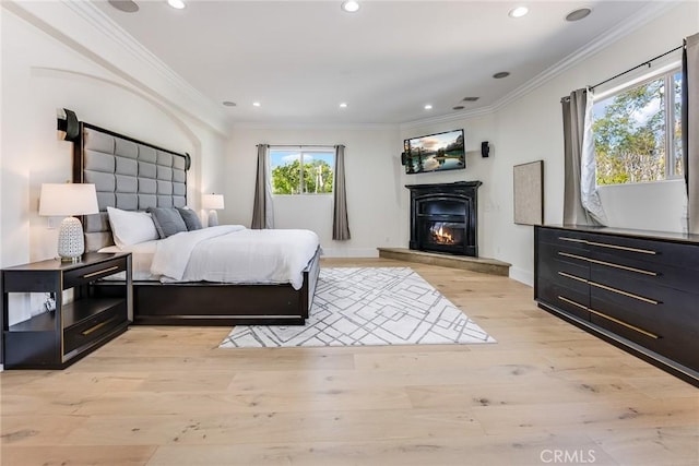 bedroom featuring light wood-type flooring, crown molding, and multiple windows