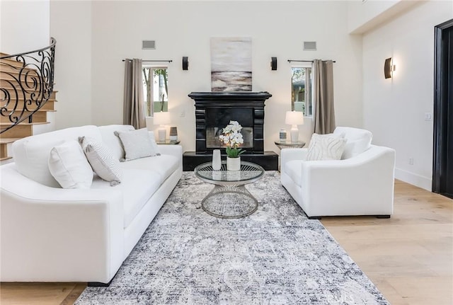 living room featuring light wood-type flooring and a towering ceiling