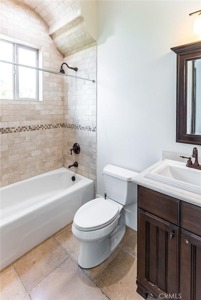 full bathroom featuring tiled shower / bath combo, vanity, and toilet